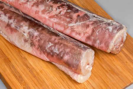 Two frozen kingklips, also known as pink cusk-eel without of heads covered with hoarfrost on a wooden cutting board, fragment close-upの写真素材