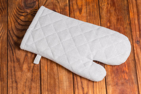 Single gray quilted textile oven glove on dark wooden rustic table, top viewの写真素材