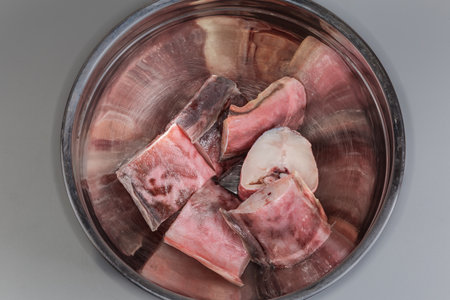 Raw pieces of kingklip, also known as pink cusk-eel in a big stainless steel kitchen bowl, top view...