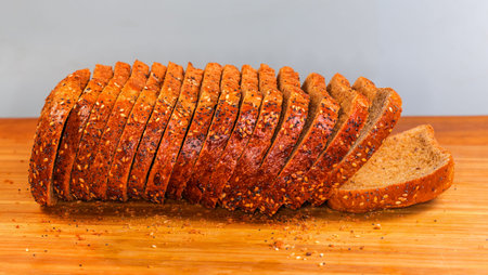 Top of sliced rectangular loaf of the multi cereal wheat and rye brown bread sprinkled with various...