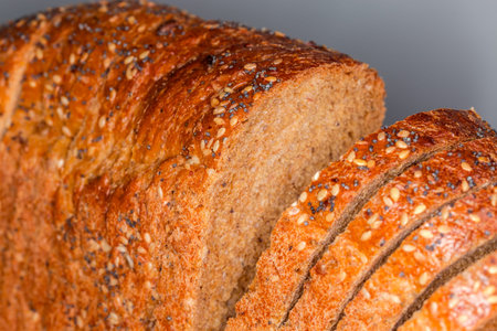 Sliced rectangular loaf of the multi cereal wheat and rye brown bread sprinkled with various seeds,...