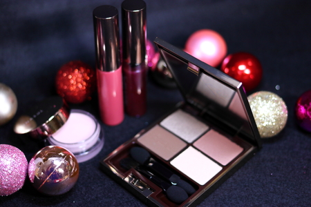 Cosmetics of eye shadow, highlight, lipstick and colorful Christmas decorations on black backgroundの写真素材