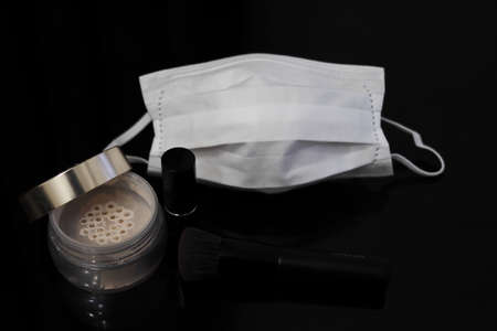 White mask and cosmetics (face powder and lip) (black background)の写真素材
