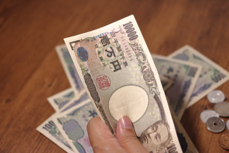 Hand holding Japanese yen (10,000 yen bill) and a lot of paperの写真素材
