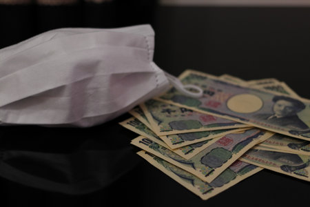 Japanese money and white mask placed on the tableの写真素材