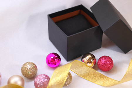 Black gift box with pink and gold colorful decoration (white background)の写真素材