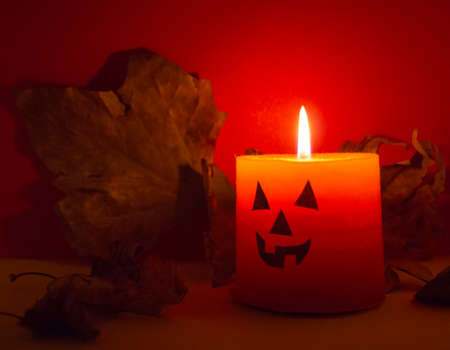 Halloween orange burning candle on red backgroundの写真素材
