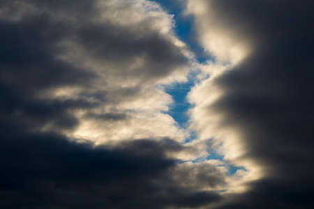 Dark clouds backlit by sun. Blue sky