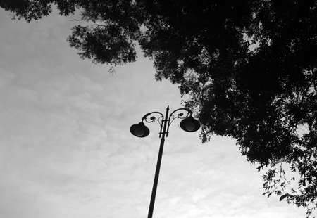 Black-and-white photograph. Street lights. General lighting. Cloudy.