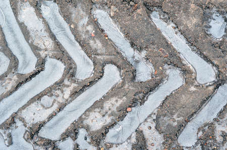 Ice in traces of protectors of tires on a dirt road.