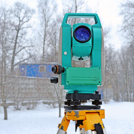 Theodolite on  support near the building site in winter