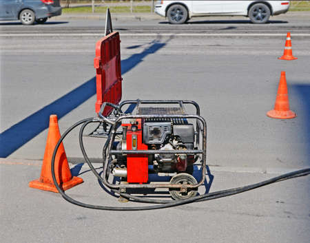 Industrial compressor on  road during repairs. Site is fenced with  warning road sign and signal...