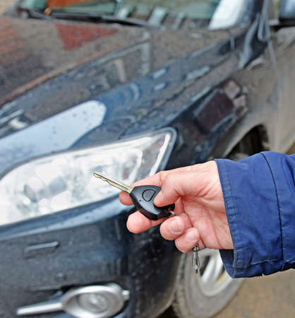 Man's hand holds  car key against of dark autoの写真素材