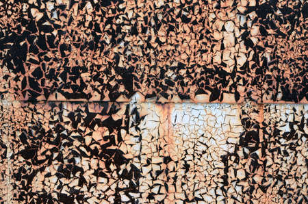 Detail of a wall of rusty sheet metal with peeling brownish rust light paint. Joint of two sheets of...