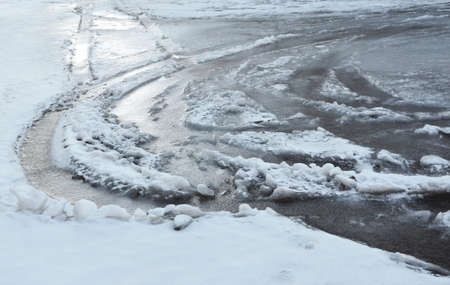 The frozen thawed snow in traces of wheels of cars. The image can be also used as a background.