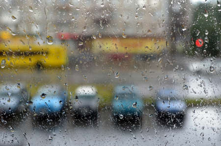City street in rainy weather through glass with water drops. The image can be used as background.の写真素材