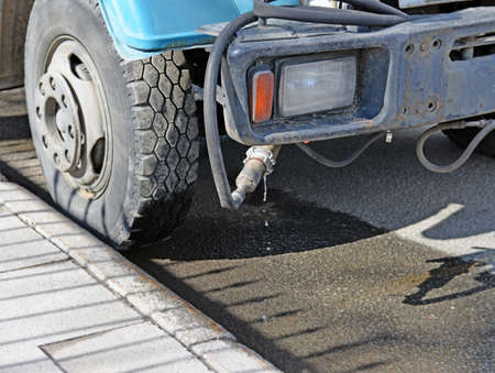 Fragment of old dusty water-jetting vehicle. Headlight and hose with dripping water closeup.の写真素材