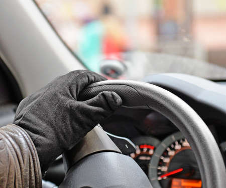 Male hand in suede glove on steering wheel closeup. Driving.の写真素材