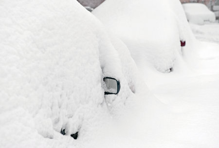 Parking during heavy snowfall. Vehicles are similar to large snowdrifts. Abstract background. Focus on rear view mirror of nearest carの写真素材