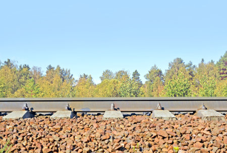 Rails on railway embankment in forest against of the and tops of trees. Side view. Background.の写真素材