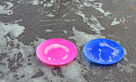 Place where bubbles have been blowing recently. Two empty plates for soap solution and foam on asphalt. Abstract background.の写真素材