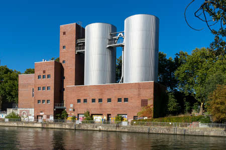 Berlin, Germany - September 30, 2018: View on Charlottenburg Power Plant (Kraftwerk Charlottenburg) from the opposite side of the river with a couple of people standing next to graffiti on the buildings wallsのeditorial素材