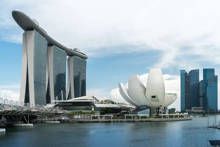 Singapore - June 6 2017: Marina Bay Sands luxury hotel, The Shoppes shopping center, Helix Bridge, and ArtScience Museum at Marina Bay with few people on the embankment in natural light, daytimeのeditorial素材