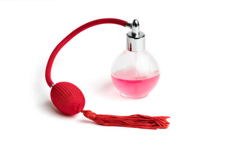 Bright pink perfume in a glass transparent bottle with red vintage style sprayer with an airbag and tassel on white background shot with studio lightの写真素材