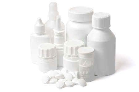 Multiple white clean medical bottles and a stack of white round pills on white background shot with studio lightの写真素材