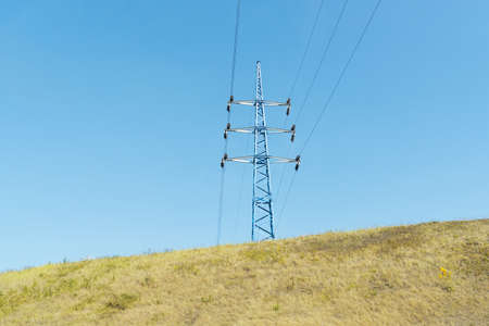 Single electrical power transmission tower on blue sky