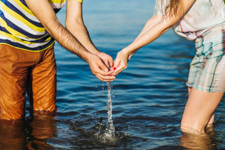young couple Girl ( woman ) and boy ( guy ) holding hands above the water.
in the hands of a drop of water flow into the seaの写真素材