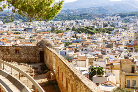 View of resort Greek architecture Rethymno city-port, built by Venetians, from height of Fortezza Castle - fortress on hill Paleokastro. Red tiled roofs and mountains in background. Crete, Greeceの写真素材