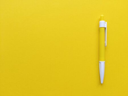 Yellow and white pen on yellow background. Minimalistic flat lay with copy space.の写真素材