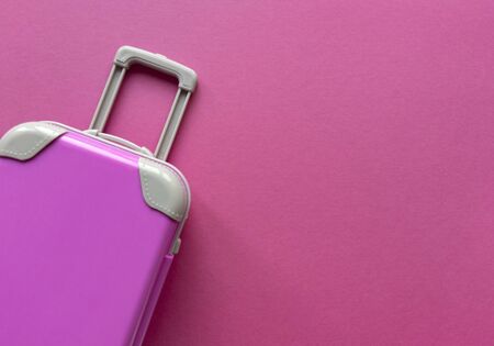 Pink plastic suitcase on pastel paper background.Travel concept holiday summer adventure trip. Flat lay with one simple thing. Stock photo.の写真素材