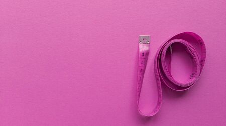 Pink centimeter on pink background. Simple flat lay with pastel texture. Fitness concept. Stock photography.の写真素材
