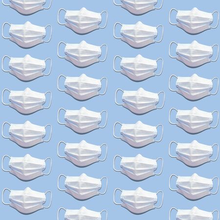 White medical masks on blue background. Trend pattern with hard shadows. Flatlay stock photo.の写真素材