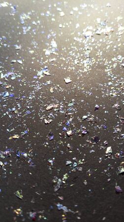 Foil pieces on black background with multi colored shine. Abstract fashion stock macro photo.の写真素材