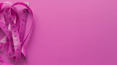 Pink centimeter on pink background. Simple flat lay with pastel texture. Fitness concept. Stock photo.の写真素材