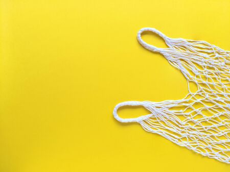 White string cotton eco bag on yellow background. Simple flat lay with copy space. Ecology zero waste concept. Stock photo.の写真素材