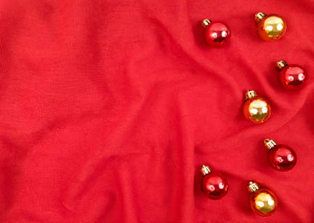 Red and gold Christmas balls on red textile background.の写真素材