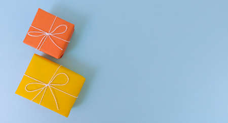 Yellow and orange gift boxes on a blue background. Simple flat lay with copy space.