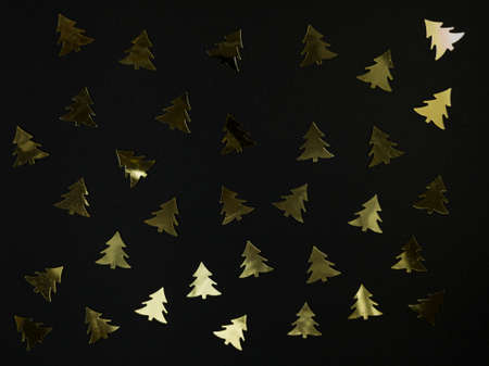Christmas tree confetti on black background. Festive flat lay.