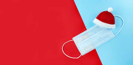 Medical mask and Santa Claus hat on a red, blue background.の写真素材
