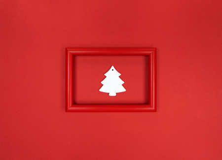 Red frame, with white wooden Christmas tree toy inside.
