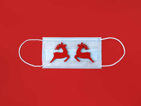 Medical mask and wooden deer toys on a red background.の写真素材