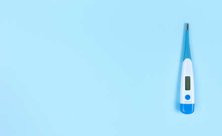 Electronic thermometer on a blue background with copy space.