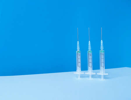 Three syringes on blue background with trendy skyline and copyspace.の写真素材