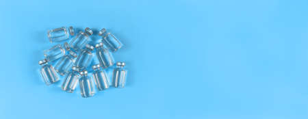 Lots of vials with liquid medicine on blue backdrop with copy space.の写真素材