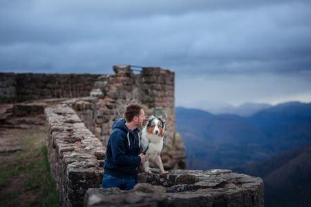 man and dog travel together. Pet and his friend in nature. Australian Shepherd and its ownerの写真素材