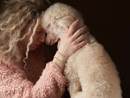 curly girl and poodle. A dog similar to its people. portrait in studio. attitude, love,...